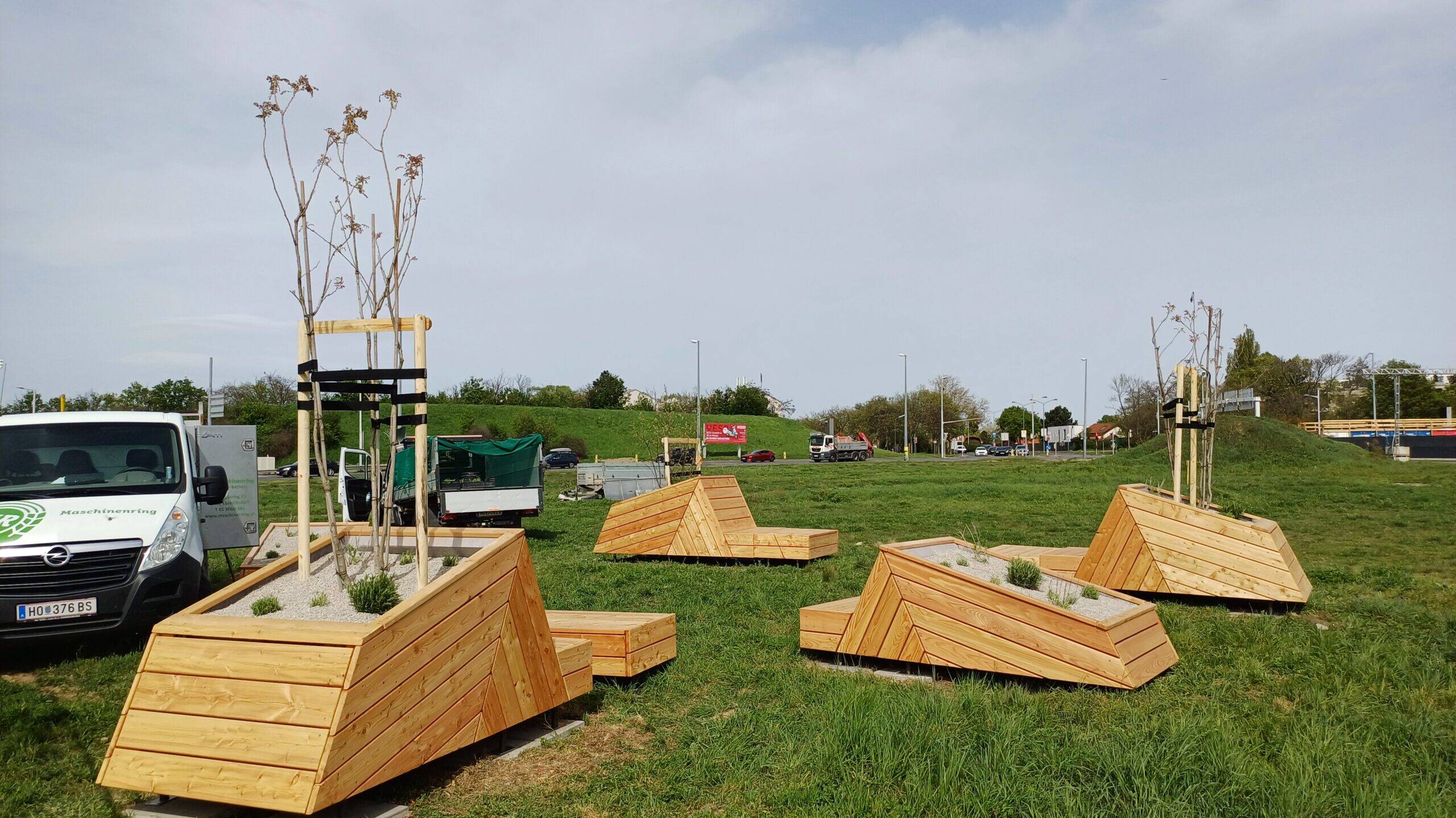 Sitzmöbel aus Holz mit Bepflanzung auf Grünfläche am Verteilerkreis