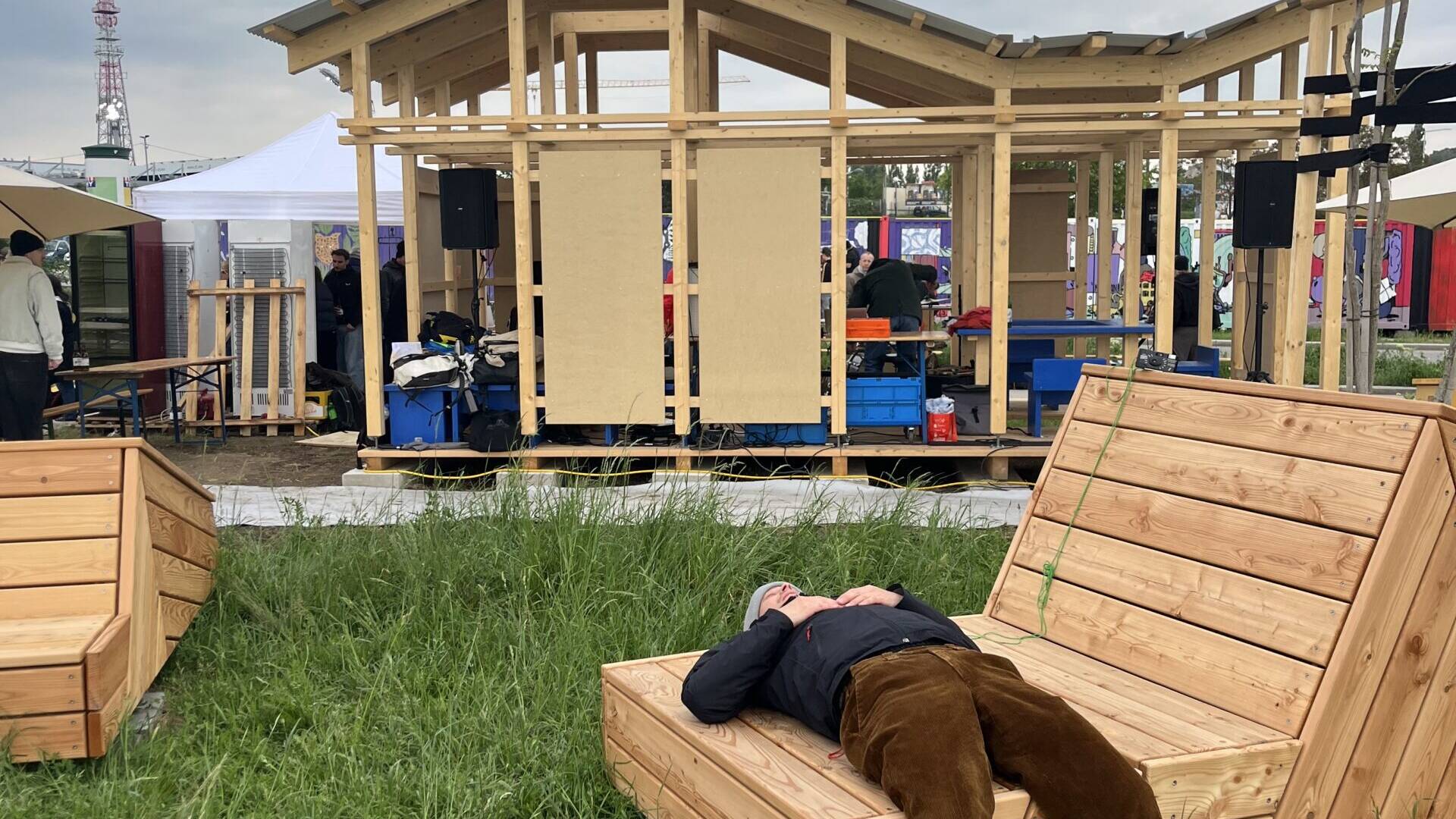 Person chillt auf Pflanzmöbel - dahinter Pavillion 