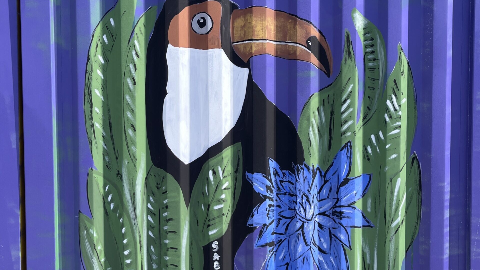 Graffiti: Tucan mit Blume und Blättern auf blauem Container